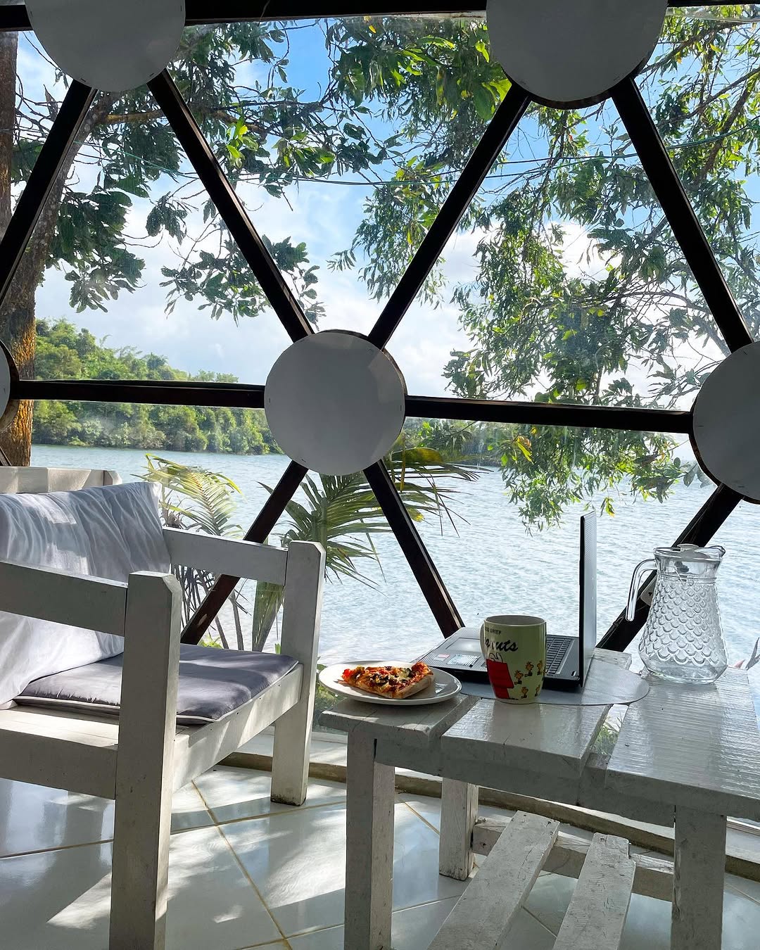 Inside a geodesic dome — table set for breakfast with lake view through the transparent panels