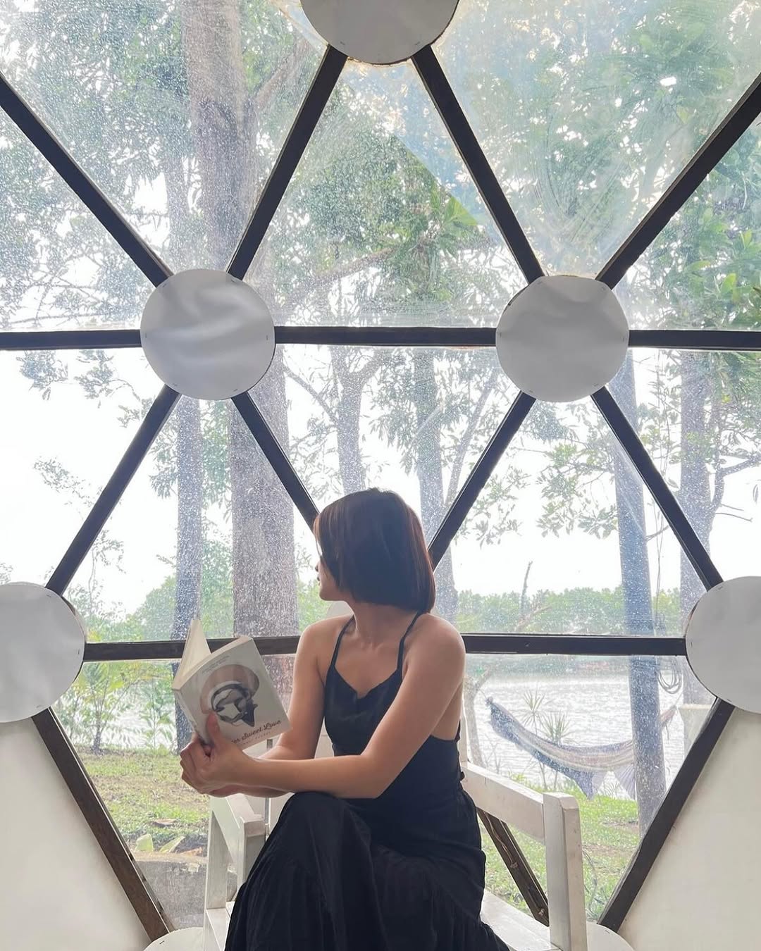 Dome Veera — guest reading a book inside the dome facing the lake
