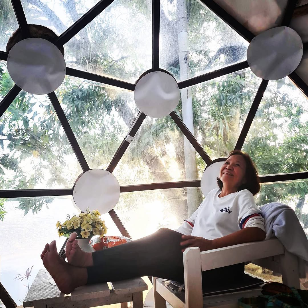 Inside the dome — guest relaxing with coffee, full dome panel view to the trees and lake