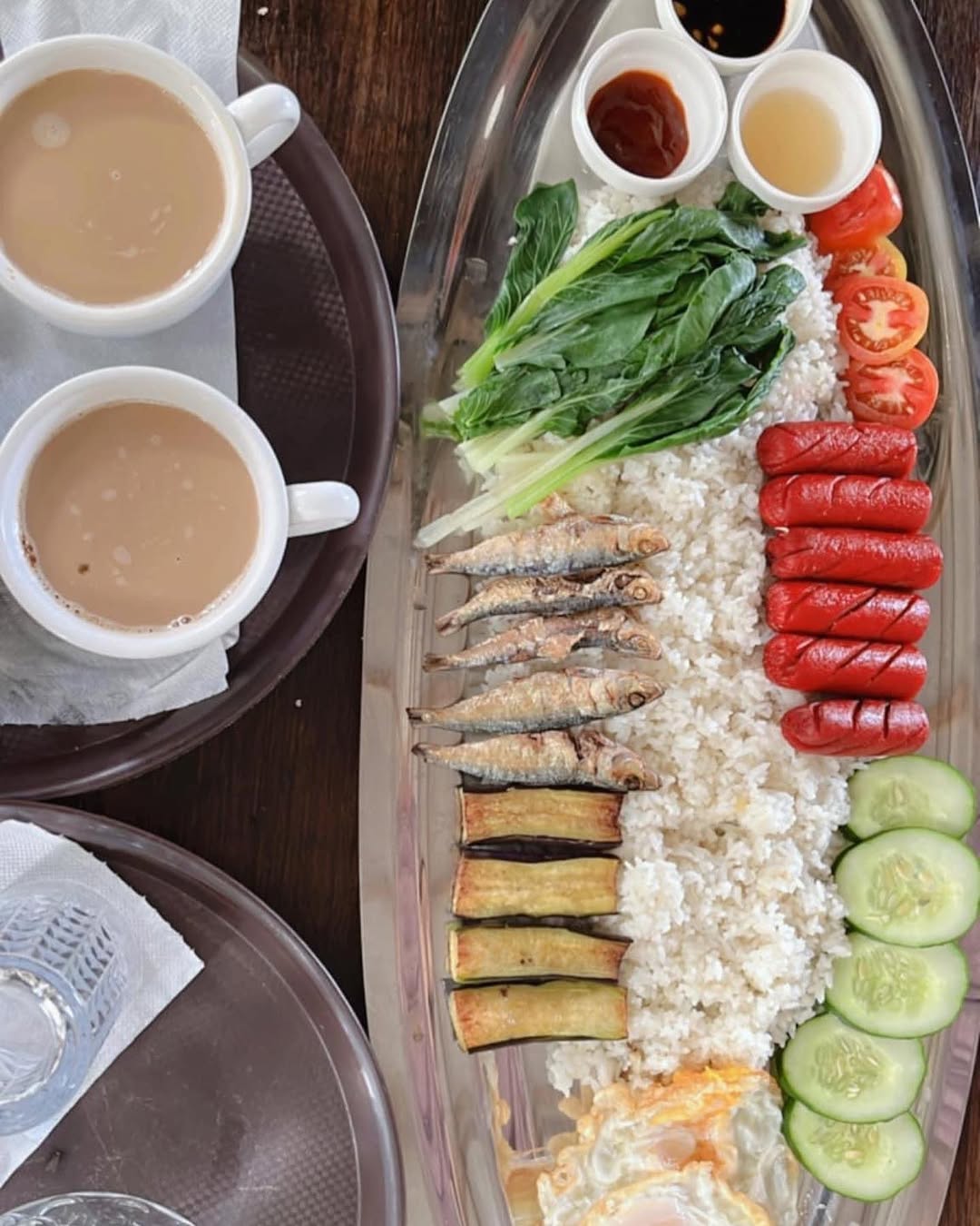 Filipino breakfast spread — dried fish, sausages, vegetables, and rice on a silver tray
