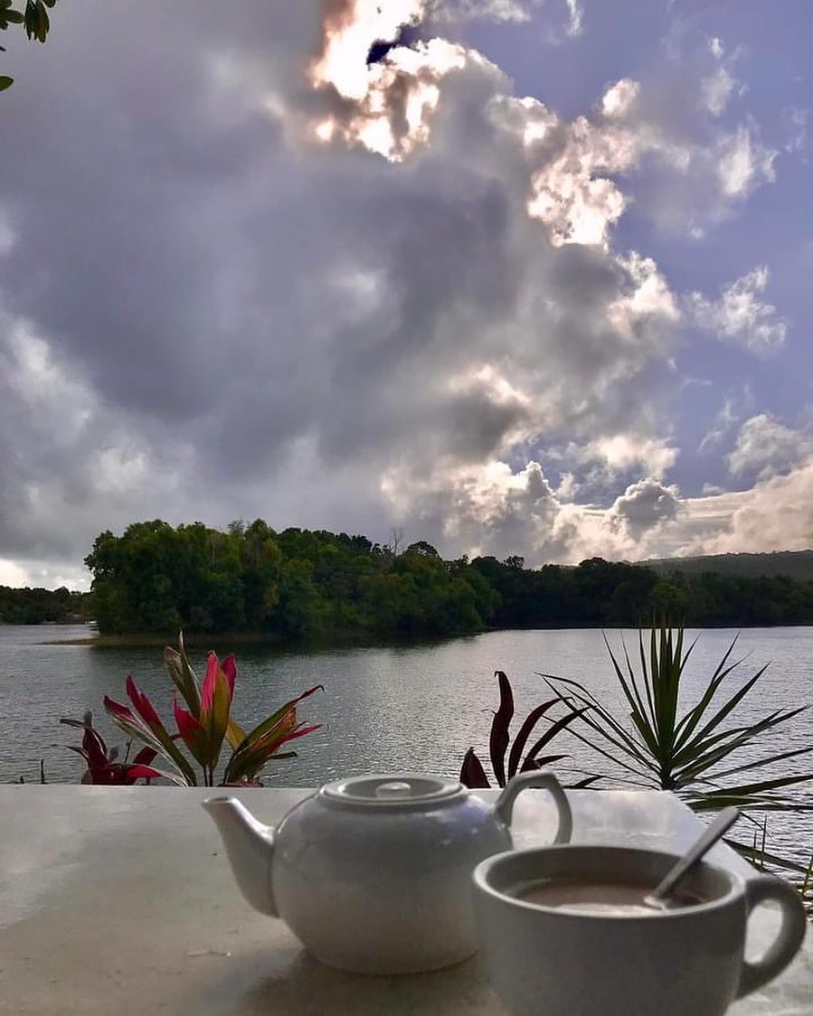White teapot and cup on a ledge overlooking the lake with dramatic cloud formations above