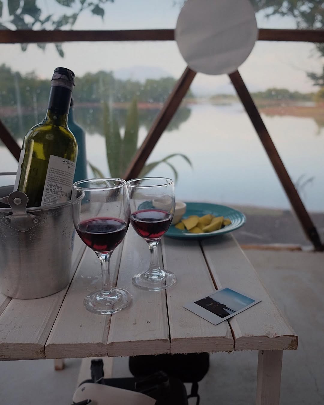 Inside Dome Veera — wine and cheese on the table with lakeside dome panel view at dusk